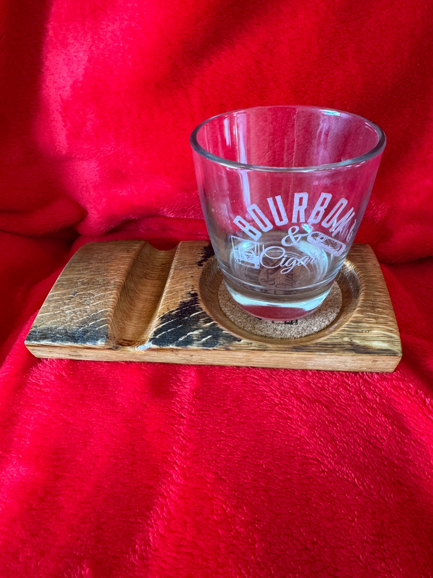 Clear glass with branding on a wooden coaster.
